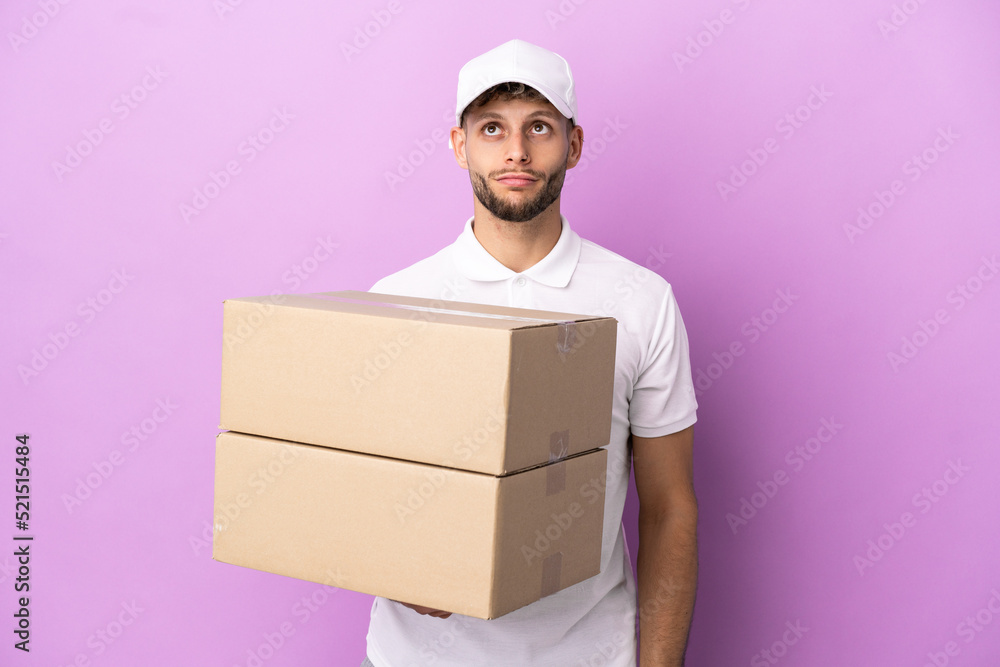 Delivery caucasian man isolated on purple background and looking up Delivery caucasian man isolated on purple background and looking up