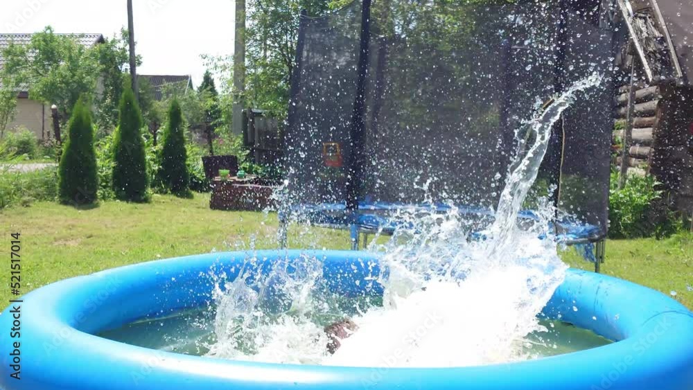 A child falls into a blue inflatable pool A child falls into a blue inflatable pool