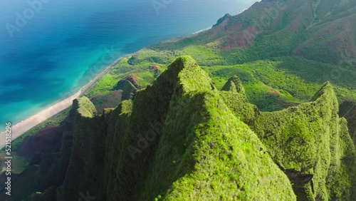 Magnificent nature drone flying over green jungle mountain peaks revealing tropical beach on Na Pali park. Incredible aerial view dramatic mountains, blue ocean on Napali Coast Kauai island Hawaii USA photo