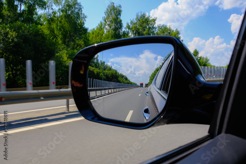 Look in the rear view mirror of a car. Car driving on the road. © evgenius1985
