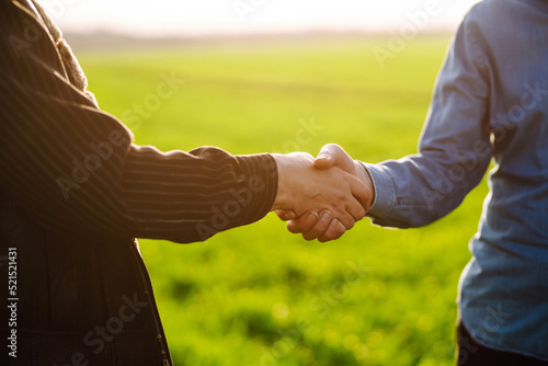Two farmers making agreement with handshake in green wheat field. The concept of the agricultural business.