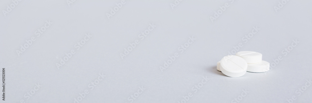 Heap of white pills on colored background. Tablets scattered on a table. Pile of red soft gelatin capsule. Vitamins and dietary supplements concept Heap of white pills on colored background. Tablets scattered on a table. Pile of red soft gelatin capsule. Vitamins and dietary supplements concept