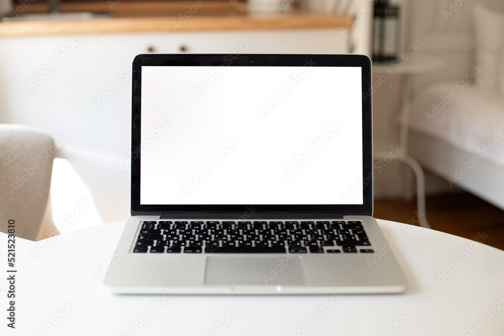 a laptop with a white blank screen stands on a table illuminated by the sun's rays in the interior of the apartment. mockup for your design a laptop with a white blank screen stands on a table illuminated by the sun's rays in the interior of the apartment. mockup for your design