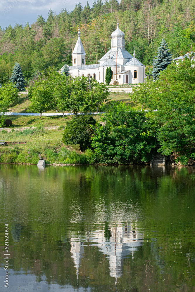 Moldavian monastery mirrored in water, summer landscape, white stone church Moldavian monastery mirrored in water, summer landscape, white stone church