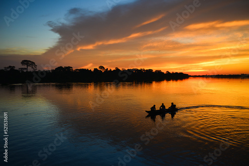 The silhouette of a small motorized canoe on the Guaporé - Itenez river at dusk, Ricardo Franco village, Vale do Guaporé Indigenous Land, Rondonia, Brazil, on the border with Bolivia
