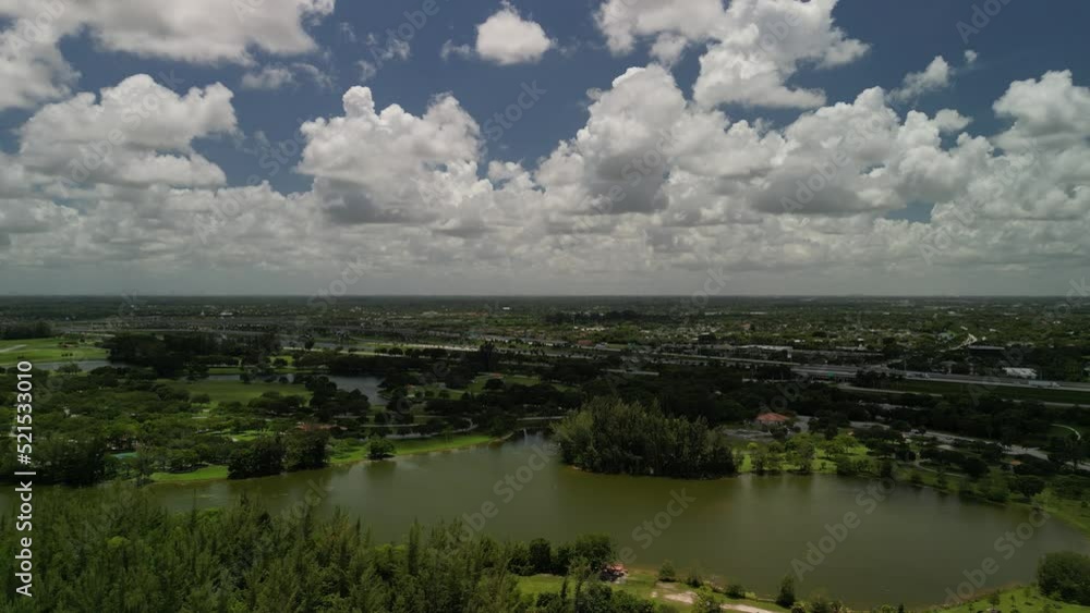 Aerial view of a park with a large lake, lots of trees and a beautiful blue sky with big white puffy clouds Aerial view of a park with a large lake, lots of trees and a beautiful blue sky with big white puffy clouds