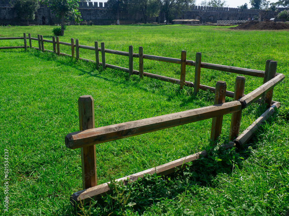 Lawn for grazing horses in the courtyard of a medieval castle. Lawn and pasture. Old architecture. Beautiful place.  Lawn with fence