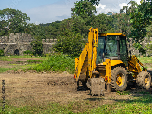 A tractor with a bucket is standing next to the working area. Tractor inside an ancient fortress. Archaeological excavations.