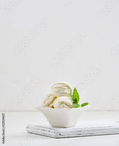 Vanilla ice cream balls with green mint leaf in a white ceramic plate