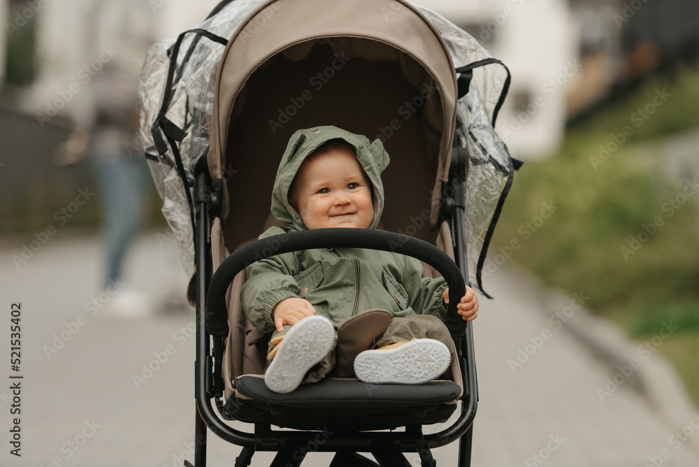 A female toddler is sitting in the stroller on a cloudy day.