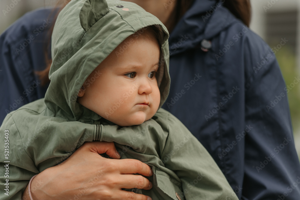 A happy mother is holding her young daughter on a cloudy day.
