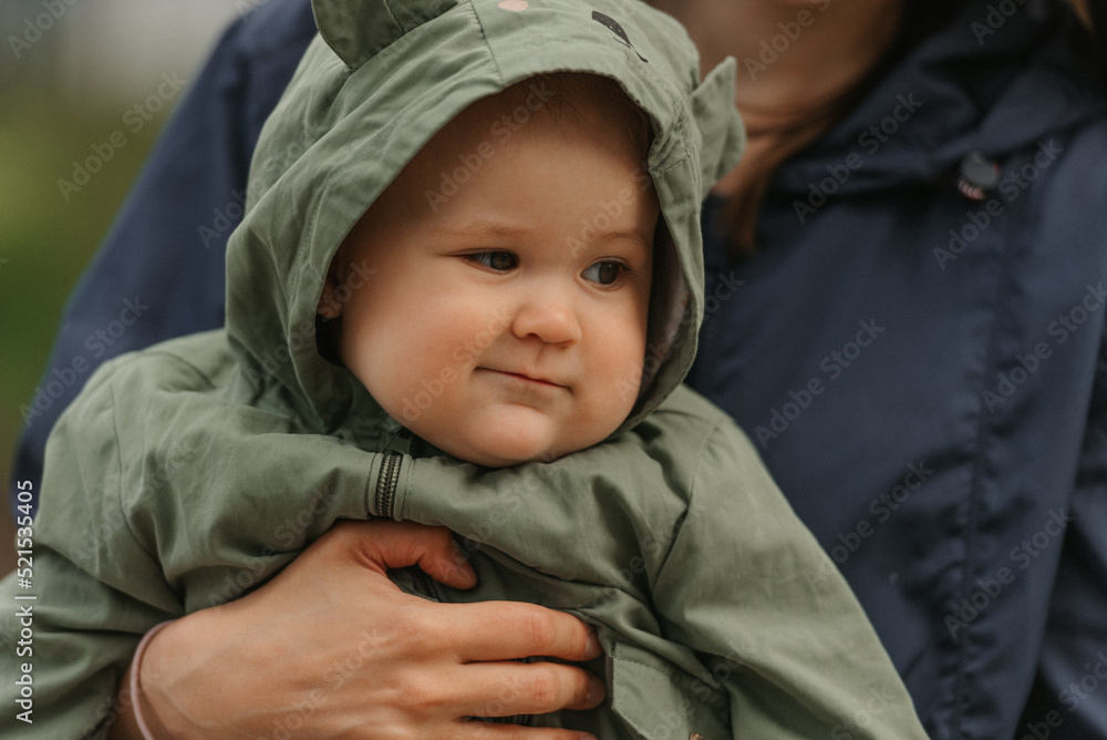 A happy mother is holding her young daughter on a cloudy day.