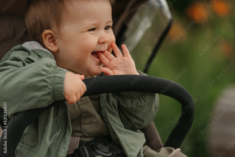 A female toddler is sitting in the stroller on a cloudy day.
