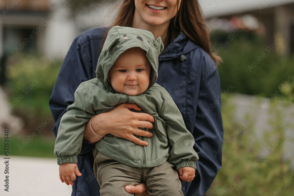 A happy mother is holding her young daughter on a cloudy day.