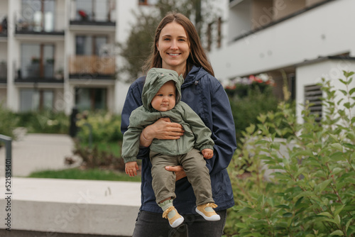 A happy mother is holding her young daughter on a cloudy day.