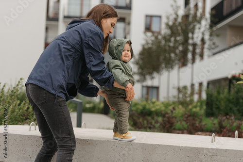 Obraz na płótnie A mom is teaching her female toddler how to do steps in the street at noon. w salonie