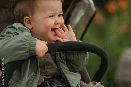 Obraz na płótnie A female toddler is sitting in the stroller on a cloudy day. w salonie