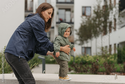 Obraz na płótnie A mom is teaching her female toddler how to do steps in the street at noon. w salonie