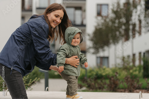 Obraz na płótnie A mom is teaching her female toddler how to do steps in the street at noon. w salonie