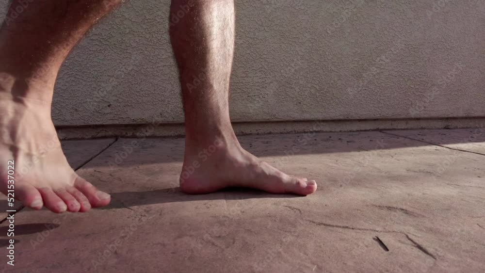 Mans feet while walking on concrete next to stucco home Mans feet while walking on concrete next to stucco home