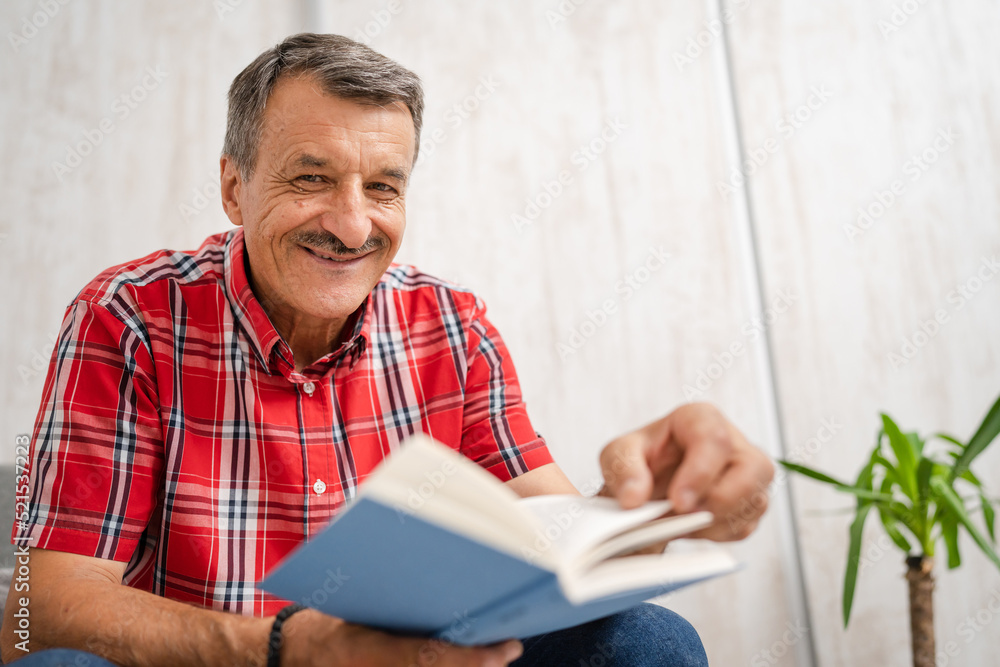 One man senior caucasian male with read book at home sitting One man senior caucasian male with read book at home sitting