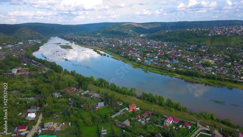 A beautiful blue lake. View from the drone Clip. A small lake next to which are green sunny trees, behind the forest and mountains and clear sky. © Media Whale Stock