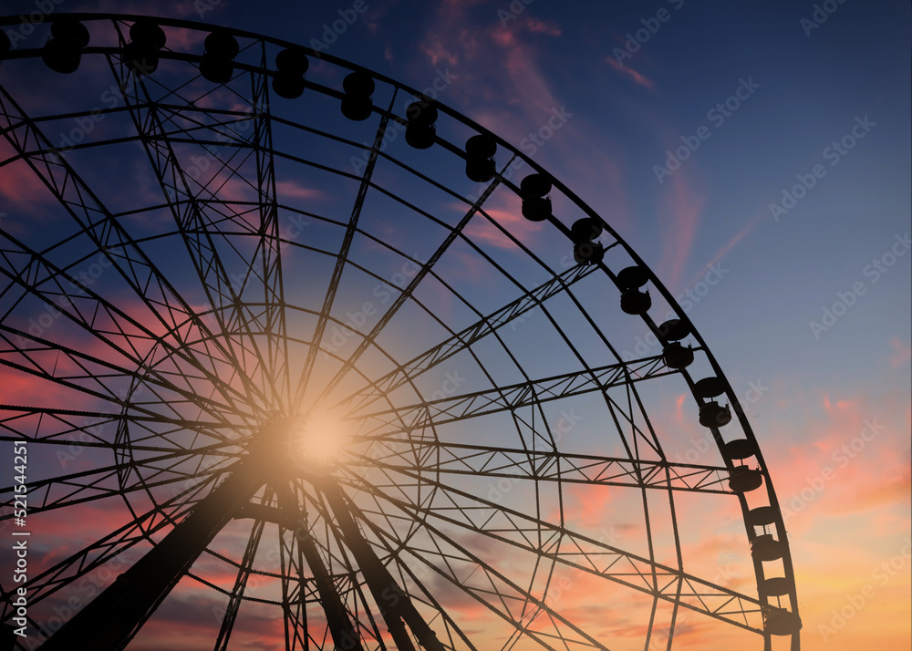 Beautiful large Ferris wheel outdoors at sunset, low angle view
