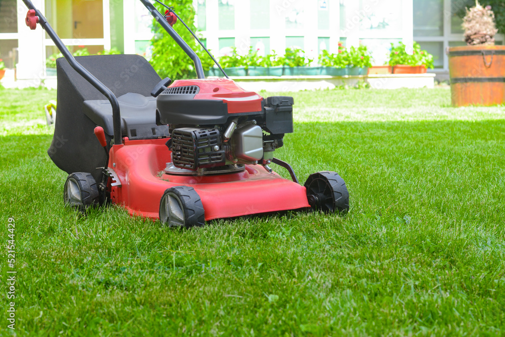 Modern garden lawn mower on green grass in park Modern garden lawn mower on green grass in park