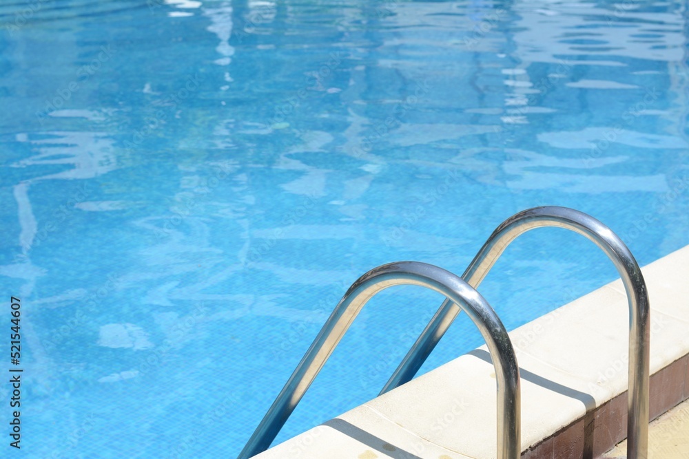 Swimming pool with metal ladder on sunny day Swimming pool with metal ladder on sunny day