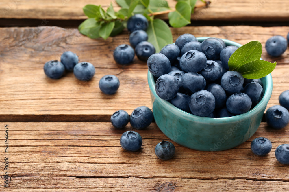 Tasty fresh blueberries and green leaves on wooden table, space for text Tasty fresh blueberries and green leaves on wooden table, space for text