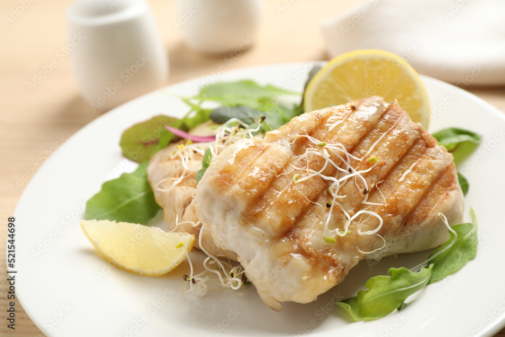 Tasty grilled fish with lemon served on table, closeup Tasty grilled fish with lemon served on table, closeup