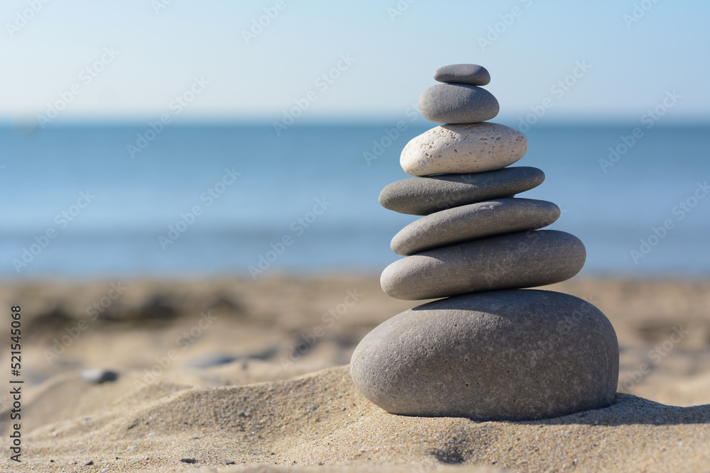 Stack of stones on sandy beach, space for text