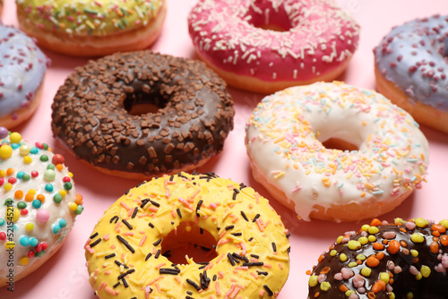 Delicious glazed donuts on pink background, closeup