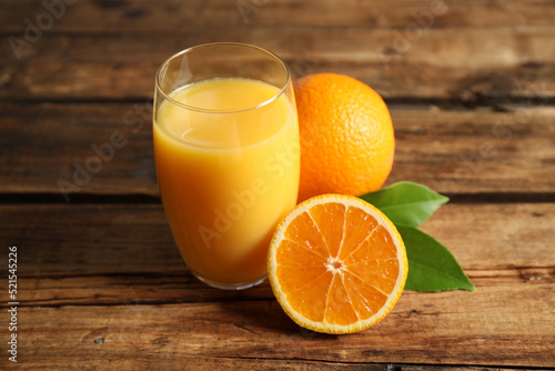 Glass of orange juice and fresh fruits on wooden table