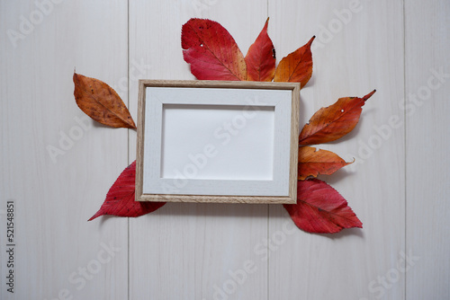 Autumn concept decoration. Colorful autumn leaves and blank wooden frame on white wooden background. Autumnal decoration background for harvest, thanksgiving and halloween festival.  photo