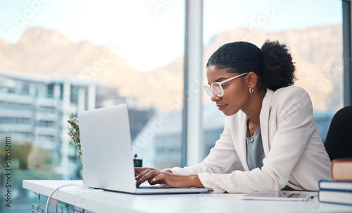 Data professional and secretary typing an email on a laptop and doing online research while working in an office. African entrepreneur looking focused while using the internet for work photo