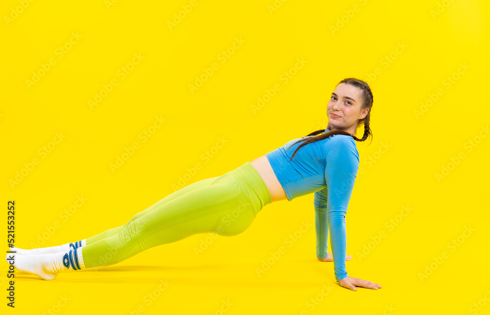 girl in a sports top and leggings. athlete in golf. Sports girl doing exercises for the buttocks with a resistance band on a yellow background. Fitness woman exercising. yellow background girl in a sports top and leggings. athlete in golf. Sports girl doing exercises for the buttocks with a resistance band on a yellow background. Fitness woman exercising. yellow background