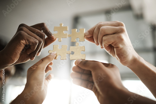 Diverse business people coming together as a team, planning for the future and collaborating to complete a puzzle closeup. Corporate professionals in unity holding up and supporting pieces of a whole photo