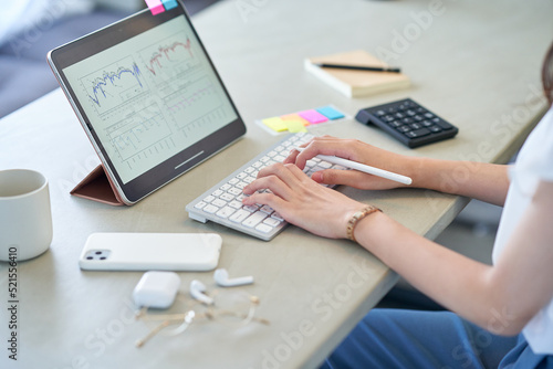 部屋でタブレットPCを操作する女性の手元