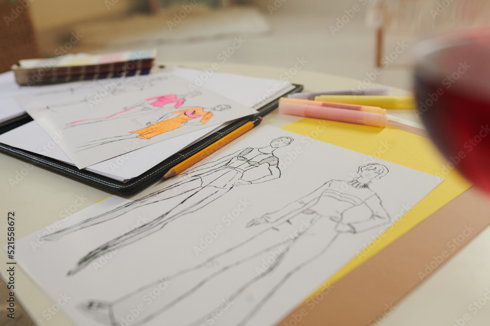 Paper sheets with fashion sketches on desk of designer, selective focus Paper sheets with fashion sketches on desk of designer, selective focus