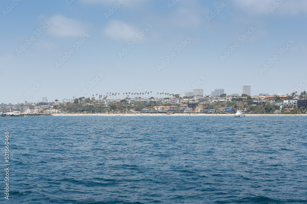 A view of the Newport Beach harbor, with large mansion homes in the background.