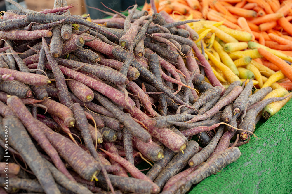A view of several piles of carrots, on display at a local farmers market.