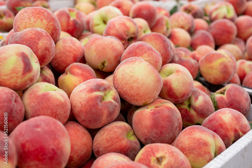 A view of a large pile of peaches  on display at a local farmers market.