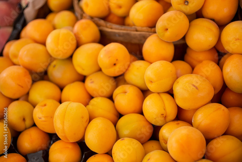 A view of a large pile of apricots  on display at a local farmers market.