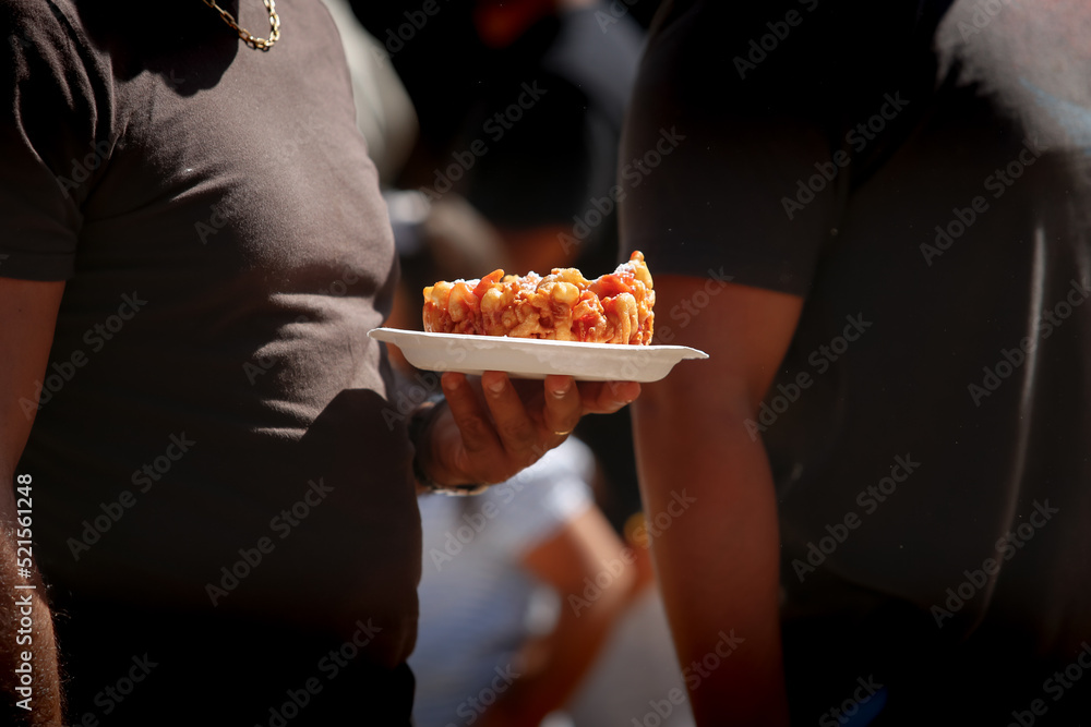 A view of a person holding a plate of funnel cake, seen at a local carnival.