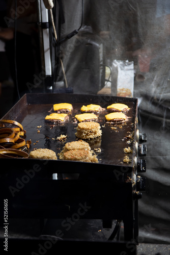A view of an outdoor griddle cooking up ramen burgers.