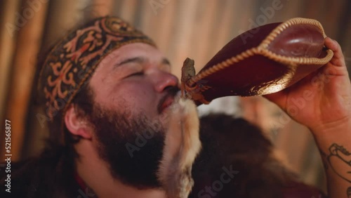 Tired man in national Altai clothes drinks from waterskin photo