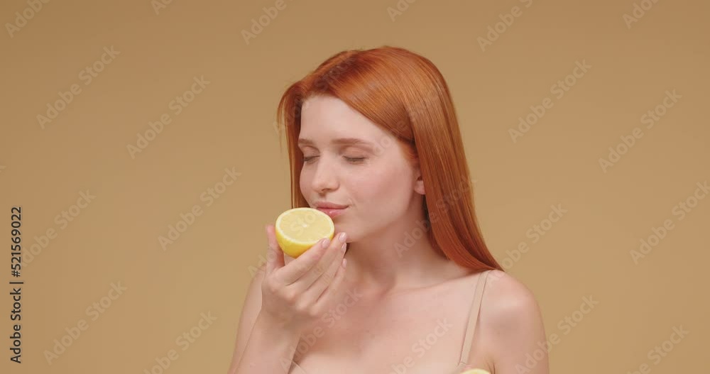 Young woman smells lemon fruit showing natural face skin Young woman smells lemon fruit showing natural face skin