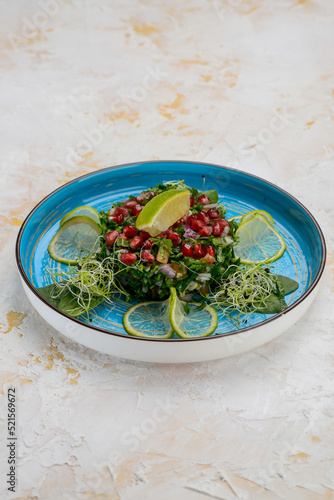spinach salad with pomegranate berries on a blue plate
