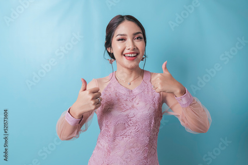 Excited Asian woman wearing modern kebaya clothes giving thumbs up hand gesture